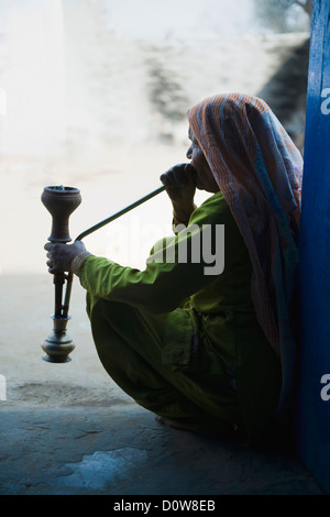 Femme fumant un narguilé pipe, Farrukh Nagar, Gurgaon, Haryana, Inde Banque D'Images