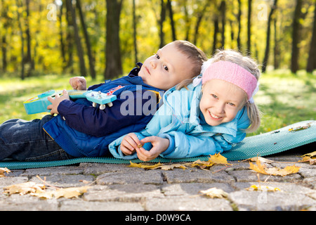 Heureux les jeunes frère et sœur jouant ensemble sur un tapis à l'extérieur dans un parc Banque D'Images