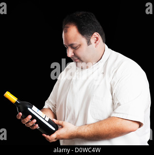 Chef looking at wine bottle Banque D'Images