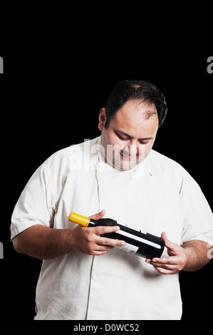 Chef looking at wine bottle Banque D'Images