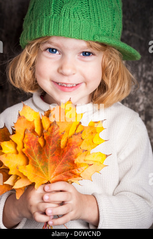 Happy smiling child holding jaune feuilles d'érable. Concept d'automne Banque D'Images