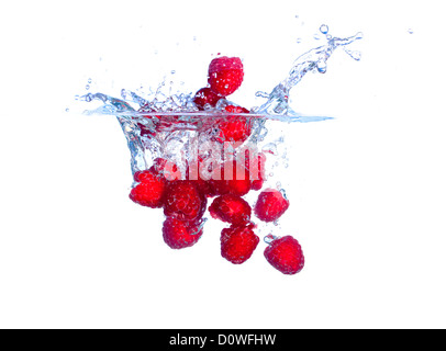 Les framboises rouges tombe sous l'eau avec une éclaboussure Banque D'Images