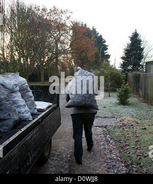 L'homme la prestation de charbon à une maison clients dans le Lancashire. Banque D'Images