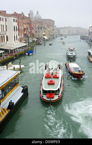 Vue depuis un pont sur le Grand Canal à Venise avec le traghetto ainsi que d'autres bateaux passant sous Banque D'Images