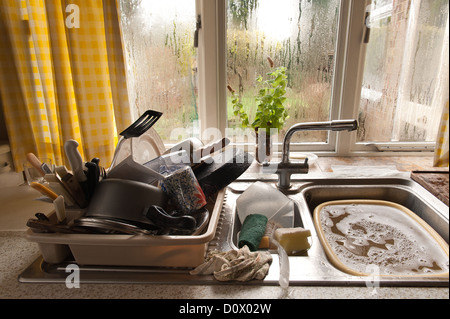 Tas de lessive corvée pour un pensionné avec condensation sur la fenêtre de cuisine pas les moyens de chauffage adéquat Banque D'Images