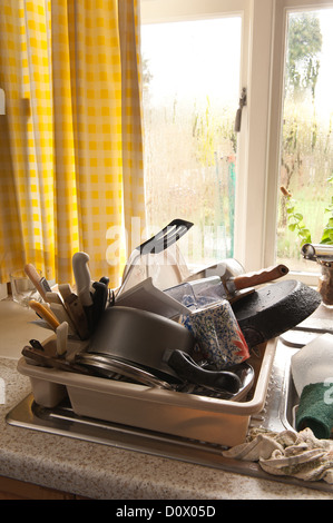 Tas de lessive corvée pour un pensionné avec condensation sur la fenêtre de cuisine pas les moyens de chauffage adéquat Banque D'Images