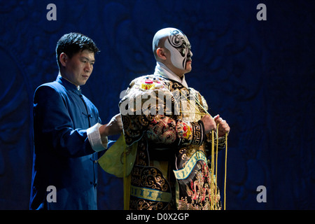 Un personnage principal masculin étant aidé par un assistant pour attacher sa robe avant d'une salle de spectacles de l'Opéra de Pékin à Beijing, Chine Banque D'Images