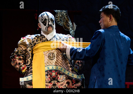 Un personnage principal masculin étant aidé par un assistant pour attacher sa robe avant d'une salle de spectacles de l'Opéra de Pékin à Beijing, Chine Banque D'Images