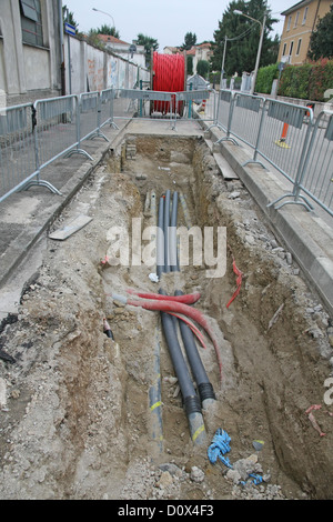 Excavation de la route sur un site de construction à des conduites pour la pose de fibre optique et câble électrique Banque D'Images