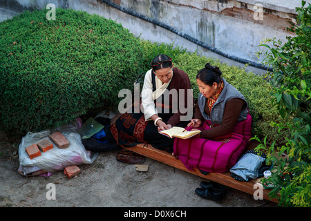 Deux femmes lisant un livre en face de stupa Boudhanath, Katmandou, Népal Banque D'Images