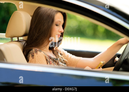 Fille assise dans le siège du conducteur de voiture à l'aide d'un téléphone cellulaire Banque D'Images