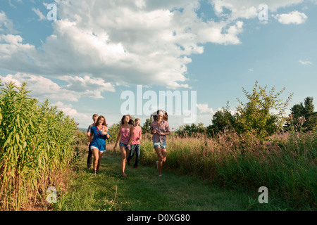 Cinq amis running through field Banque D'Images