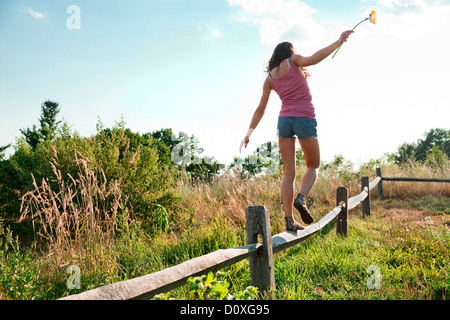 Teenage girl balancing on wooden fence Banque D'Images