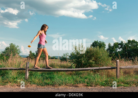 Teenage girl balancing on wooden fence Banque D'Images