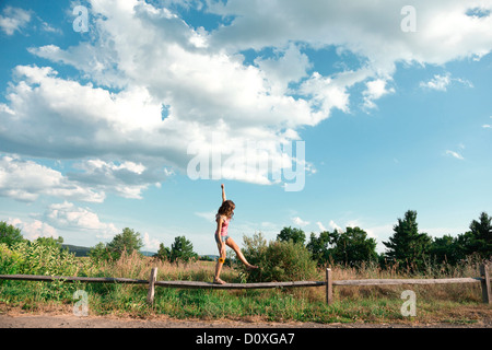 Teenage girl balancing on wooden fence Banque D'Images