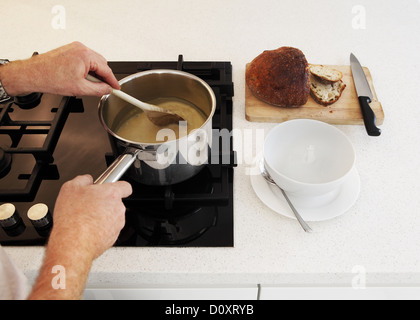 L'homme en remuant la casserole de soupe sur une plaque de cuisson Banque D'Images