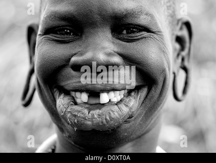 Portrait noir et blanc d'une tribu Surma Femme avec lèvre élargie et les oreilles et sourire à pleines dents, vallée de l'Omo, Ethiopie Banque D'Images