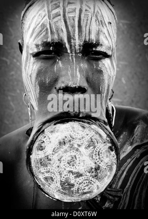 Portrait noir et blanc d'une femme de la tribu Mursi avec la lèvre plate et élargie dans les oreilles du Parc National de Mago, vallée de l'Omo, Ethiopie Banque D'Images