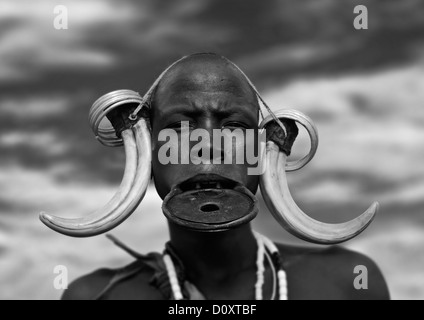 Portrait noir et blanc d'une femme de la tribu Mursi avec la lèvre plate et élargie dans les oreilles du Parc National de Mago, vallée de l'Omo, Ethiopie Banque D'Images