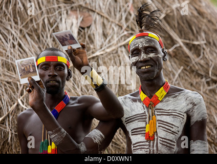 Les hommes de la tribu Karo avec peintures corps montrant Polaroïds de la tribu, l'Éthiopie, Korcho Banque D'Images