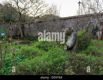 Cockington, Devon, Angleterre. Le 30 novembre 2013. Un jardin clos avec une sculpture en bois d'une personne. Banque D'Images