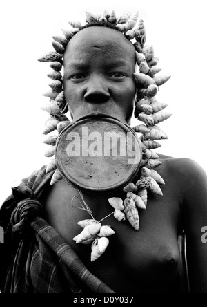 Portrait noir et blanc d'une femme de la tribu Mursi avec la lèvre plate et élargie dans les oreilles du Parc National de Mago, vallée de l'Omo, Ethiopie Banque D'Images