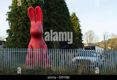 Bovey Tracey, Devon, Angleterre. Le 29 novembre 2012. Grand modèle lapin rouge sur le côté de la route attaché à une clôture. Banque D'Images