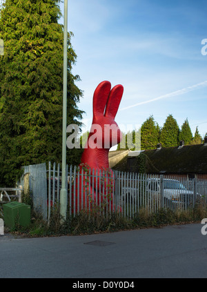 Bovey Tracey, Devon, Angleterre. Le 29 novembre 2012. Grand modèle lapin rouge sur le côté de la route attaché à une clôture. Banque D'Images