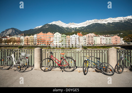 Vélos appuyé contre une barrière, de l'autre côté de la rivière la célèbre Innsbruck maisons colorées avec une montagne. Banque D'Images