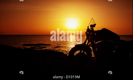 Photo de moto de luxe sur la plage dans la nuit, silhouette de moto sur le coucher du soleil, Harley Davidson, vie active Banque D'Images