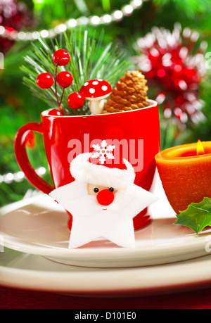 Photo de bateau de Noël, décoration de table, tasse de café rouge décoré d'étoiles, Père Noël bougie jaune et berry twig Banque D'Images