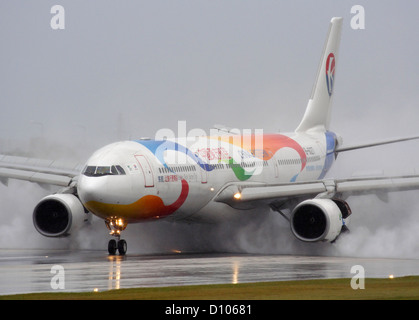 China Eastern Airlines Airbus A330-300 à vomir son jet avec inverseurs de l'atterrissage sur une piste mouillée par mauvais temps et la mauvaise visibilité Banque D'Images