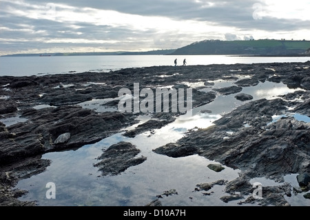 Deux personnes marchant le long d'une plage vide la plage Gyllyngvase à Falmouth, Cornwall, UK en hiver. Banque D'Images