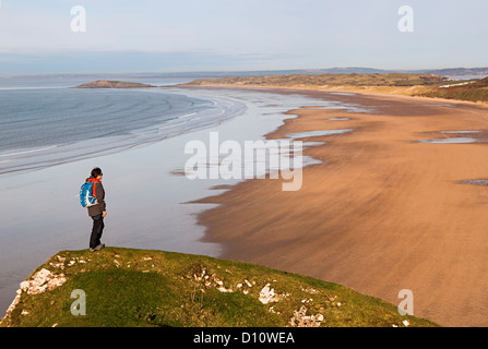 Femme debout sur la pointe de la tête vers la plage de Rhossili, Gower, Pays de Galles, Royaume-Uni Banque D'Images