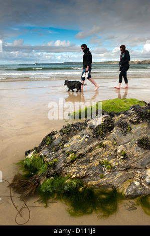 Couple walking dog sur la plage de Newquay, Cornwall. Banque D'Images