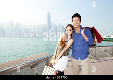 Jeune couple à la mode avec des sacs à profiter du port de Victoria, Hong Kong Banque D'Images