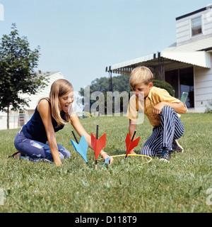 1970 Garçon Fille jouant le jeu de fléchettes de pelouse à l'arrière-cour Banque D'Images