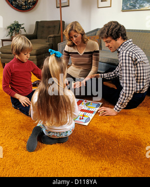 1970 FAMILY PLAYING PARCHISI SUR PLANCHER DU SALON TAPIS ORANGE Banque D'Images