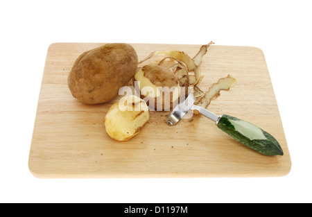 Pommes de terre pelées et entières avec un couteau économe sur une planche en bois isolés contre white Banque D'Images