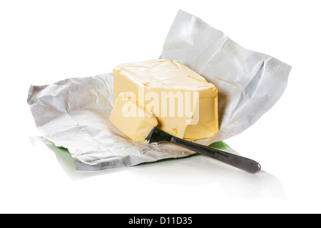 Bloc de beurre dans du papier. Morceau de beurre est coupé avec un couteau. Banque D'Images
