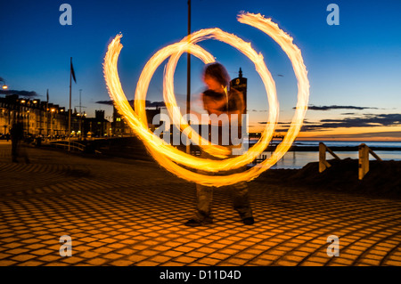 Un jeune homme de poi de la jonglerie, et d'autres compétences, Crépuscule, soir. Front de Aberystwyth Wales UK Banque D'Images