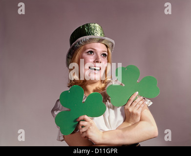 1960 IRISH WOMAN SMILING HOLDING GREEN TRÈFLES WEARING GREEN PARTY HAT Banque D'Images