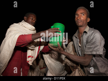 Photo de nuit d'un homme de la tribu Karrayyu ramener de la nourriture à un autre Gadaaa Karrayyu famille pendant la cérémonie, Metahara, Ethiopie Banque D'Images