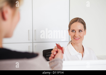 Allemagne, carte d'assurance maladie du patient à donner de réceptionniste de cabinet dentaire Banque D'Images