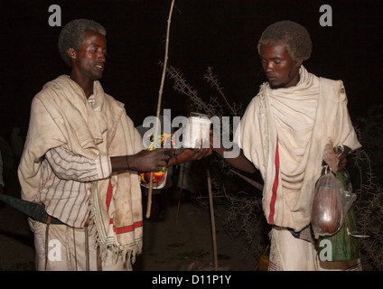 Photo de nuit d'un homme de la tribu Karrayyu ramener de la nourriture à un autre Gadaaa Karrayyu famille pendant la cérémonie, Metahara, Ethiopie Banque D'Images