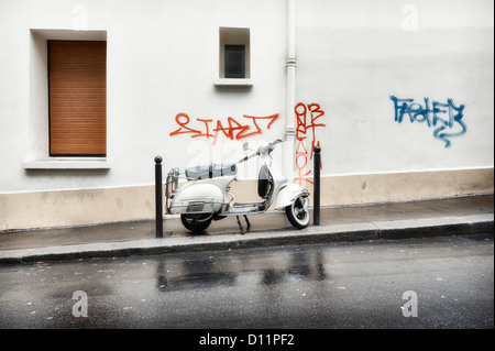 Paris, France : Vespa scooter stationné sur une rue de la ville sous la pluie Banque D'Images