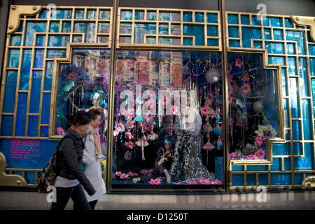 5 décembre 2012. London UK. Grands magasins à Londres décorer shop windows un mois avant Noël avec des affichages de fête pour attirer les acheteurs. Shoppers devant une fenêtre décorée affichage à Harvey Nicholls department store à Knightsbridge Banque D'Images