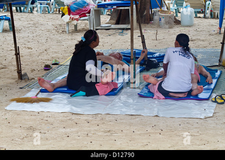 Les touristes profitant d'un massage thaï traditionnel sur la plage de Patong sur l'île de Phuket, Thaïlande Banque D'Images