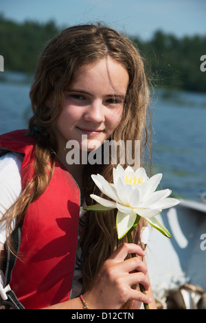 Une jeune fille portant un gilet est titulaire d'une fleur blanche, Kenora (Ontario) Canada Banque D'Images