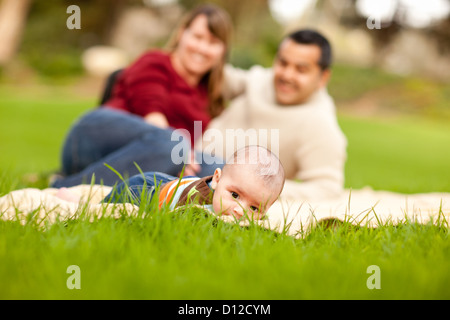 Heureux de ramper Baby Boy and Mixed Race Parents jouant dans le parc. Banque D'Images